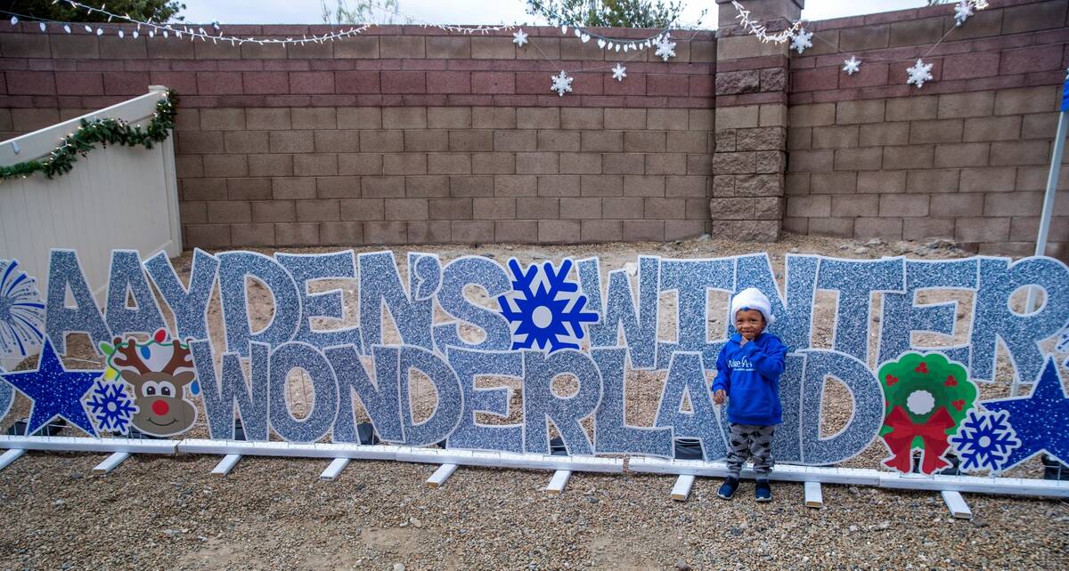 Aayden Hobbs, 3, a heart transplant recipient, stands beside a light display in his backyard at ...