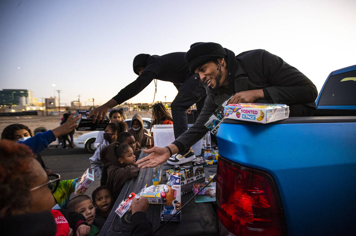 Kito Ford, of New Era Nation Atlanta chapter, right, hands out toys to children during a commun ...