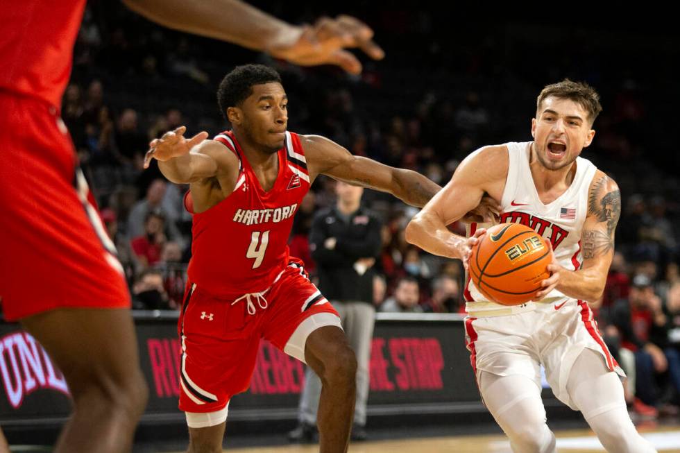 UNLV Rebels guard Jordan McCabe (5) drives around Hartford Hawks guard Moses Flowers (4) during ...