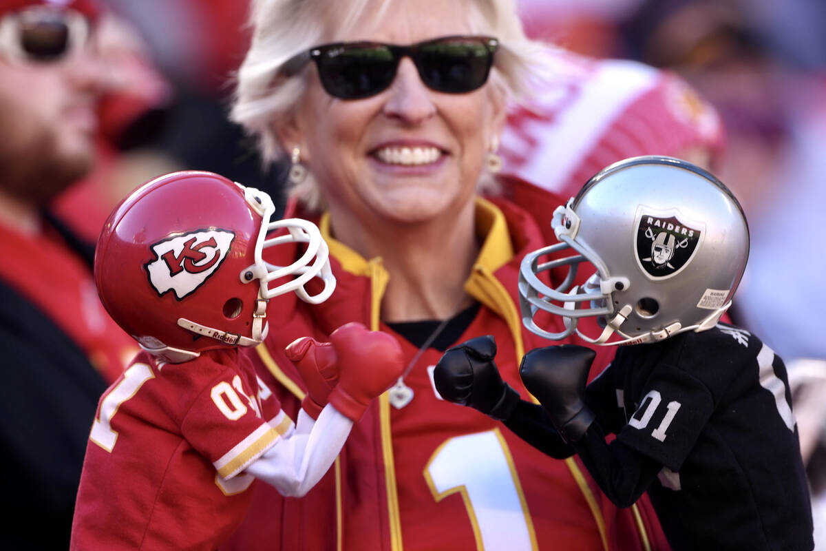 A fan holds dolls wearing a Kansas City Chief's helmet and a Raiders' helmet in the stands at A ...