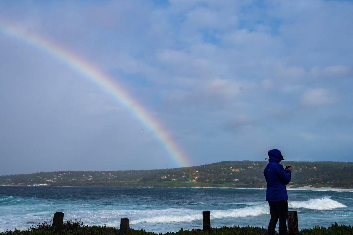 A woman walks along Carmel Point during a respite from heavy rains in Carmel, Calif., Monday, D ...