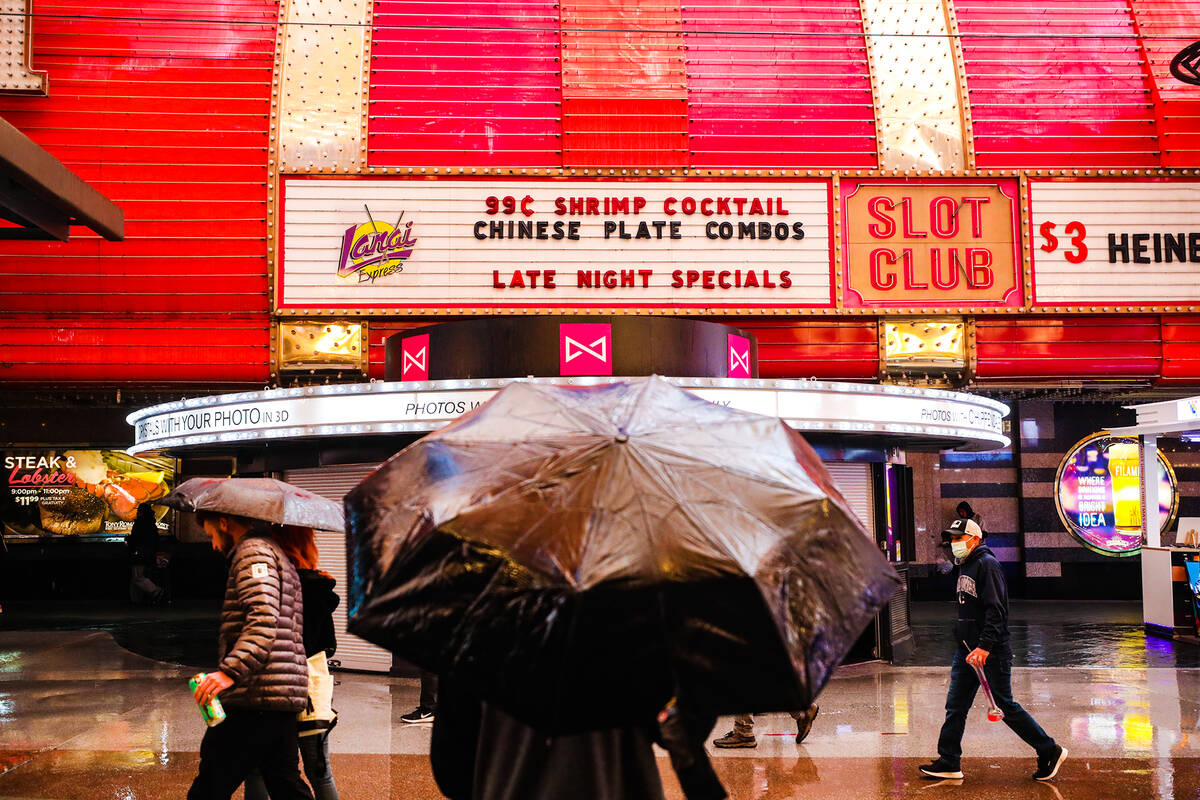 Visitors walk through the rain at the Fremont Street Experience in Downtown Las Vegas, Tuesday, ...