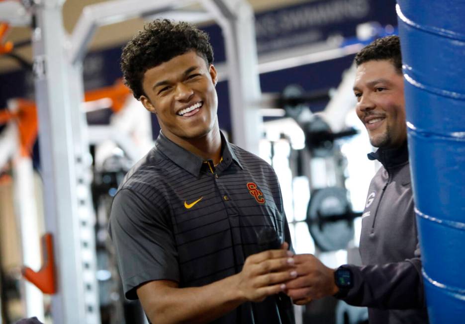 Bishop Gorman High School football player Fabian Ross left, receives a microphone from head coa ...