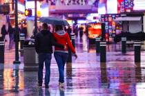Visitors walk through the rain at the Fremont Street Experience in Downtown Las Vegas, Tuesday, ...