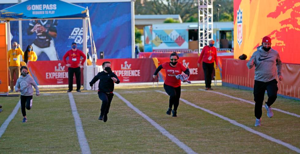 A family runs the 40-yard dash at the NFL Experience for Super Bowl LV Friday, Jan. 29, 2021, i ...