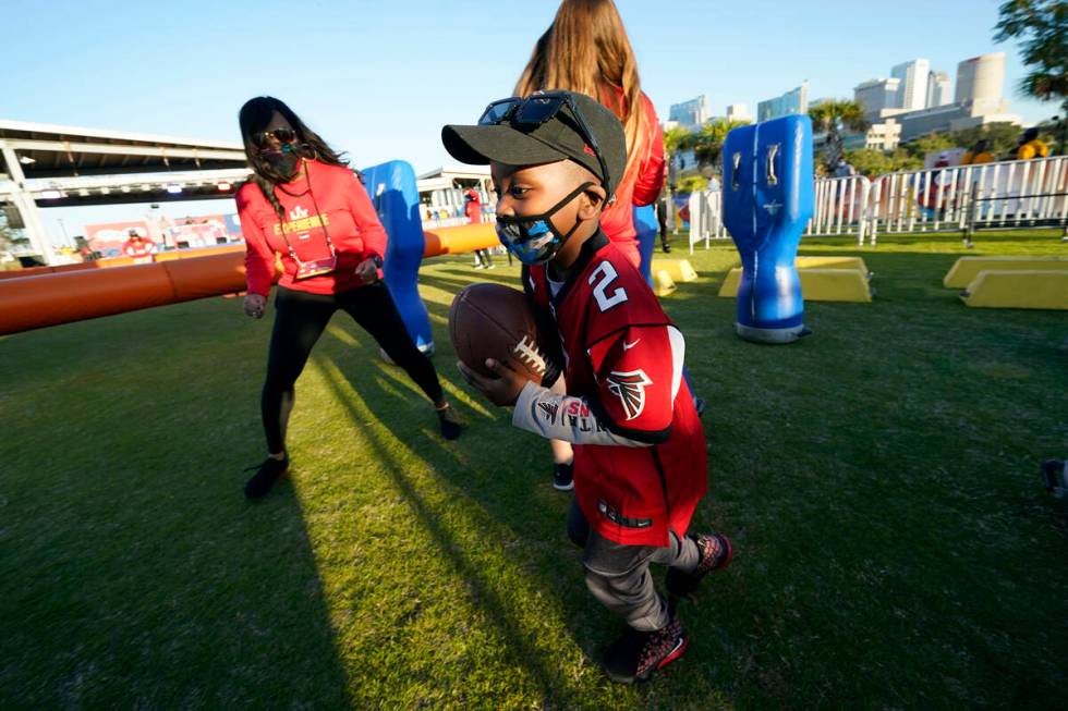 Isaiah Sheppard, 7, runs with a football at the NFL Experience for Super Bowl LV Friday, Jan. 2 ...