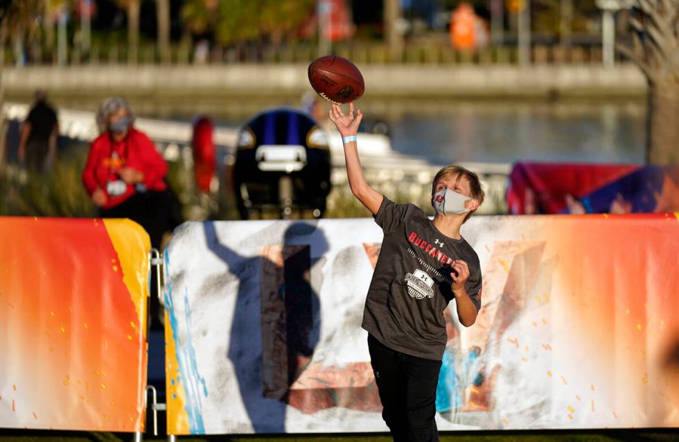 A fan throws a football at the NFL Experience for Super Bowl LV Friday, Jan. 29, 2021, in Tampa ...
