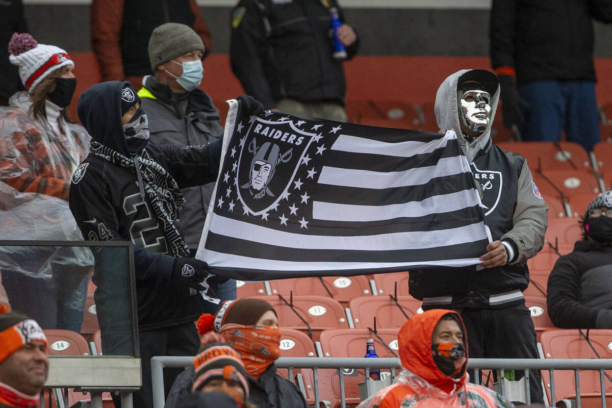 Las Vegas Raiders fans hold up a team flag during the 1st quarter of an NFL football game again ...