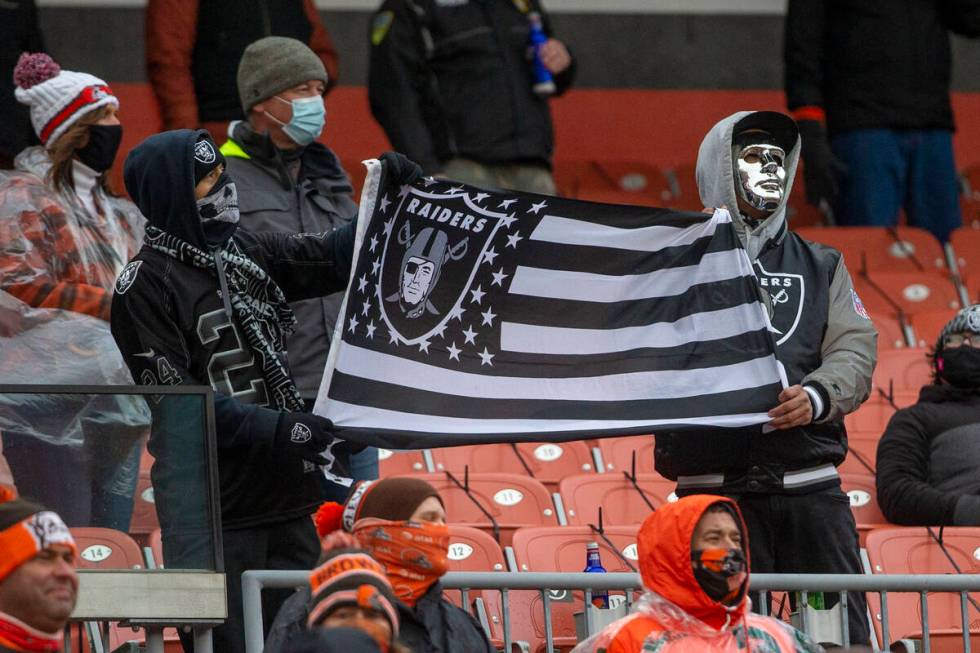 Las Vegas Raiders fans hold up a team flag during the 1st quarter of an NFL football game again ...