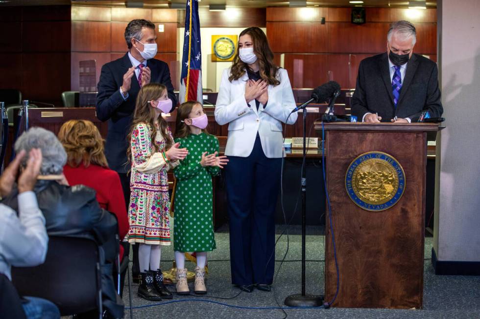 Nevada Gov. Steve Sisolak, right, signs the official document appointing Lisa Cano Burkhead, se ...