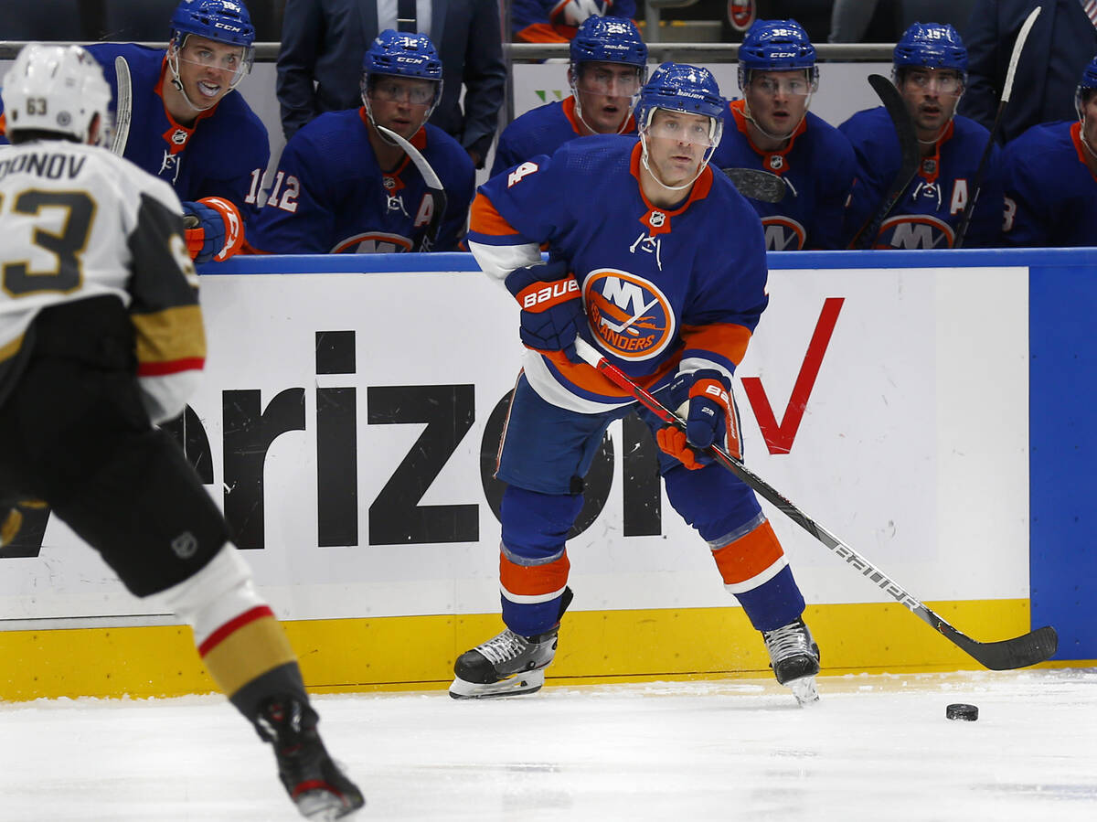 New York Islanders' Andy Greene (4) looks to pass around Vegas Golden Knights' Evgenii Dadonov ...
