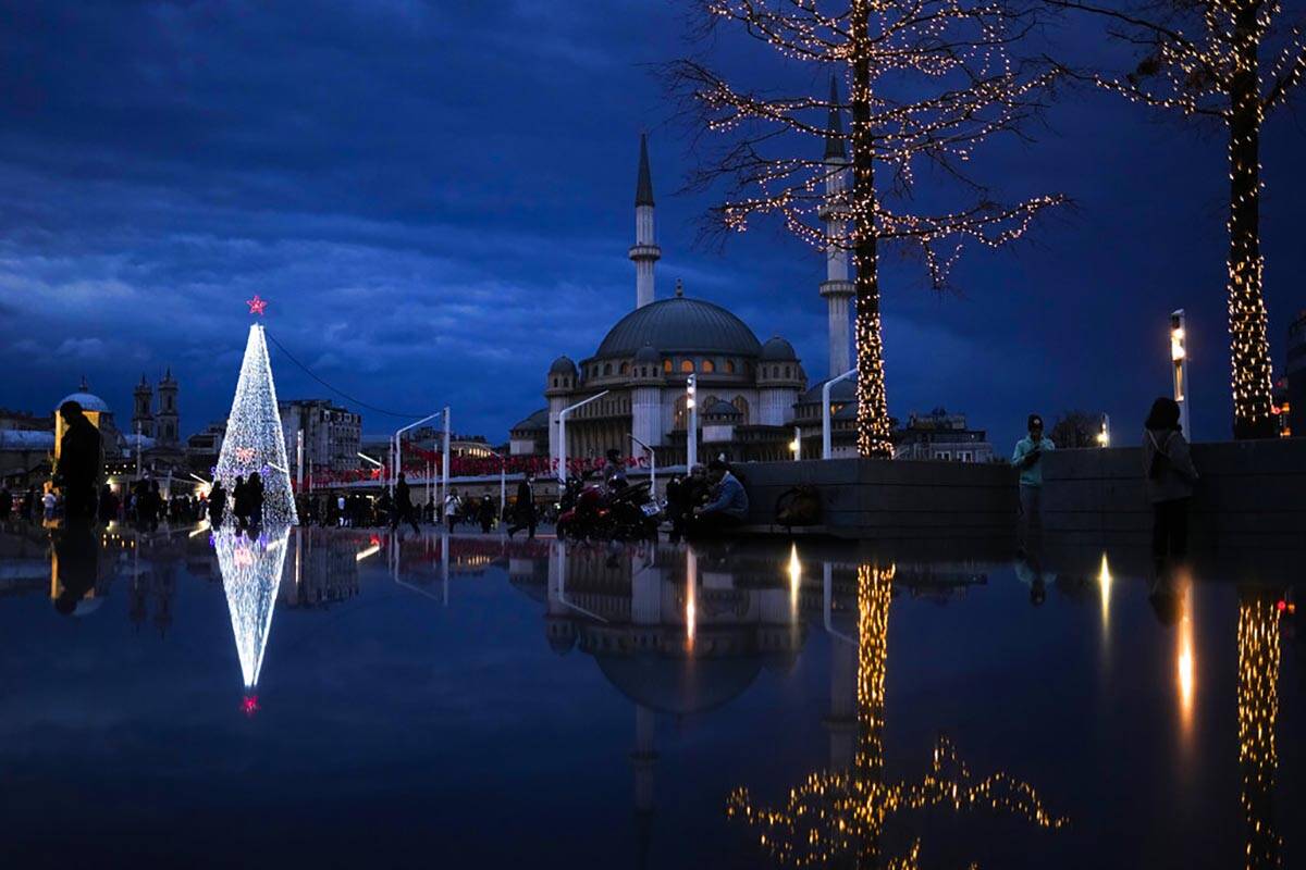 Pedestrians walk past a Christmas tree next to Taksim mosque at Taksim square in Istanbul, Turk ...