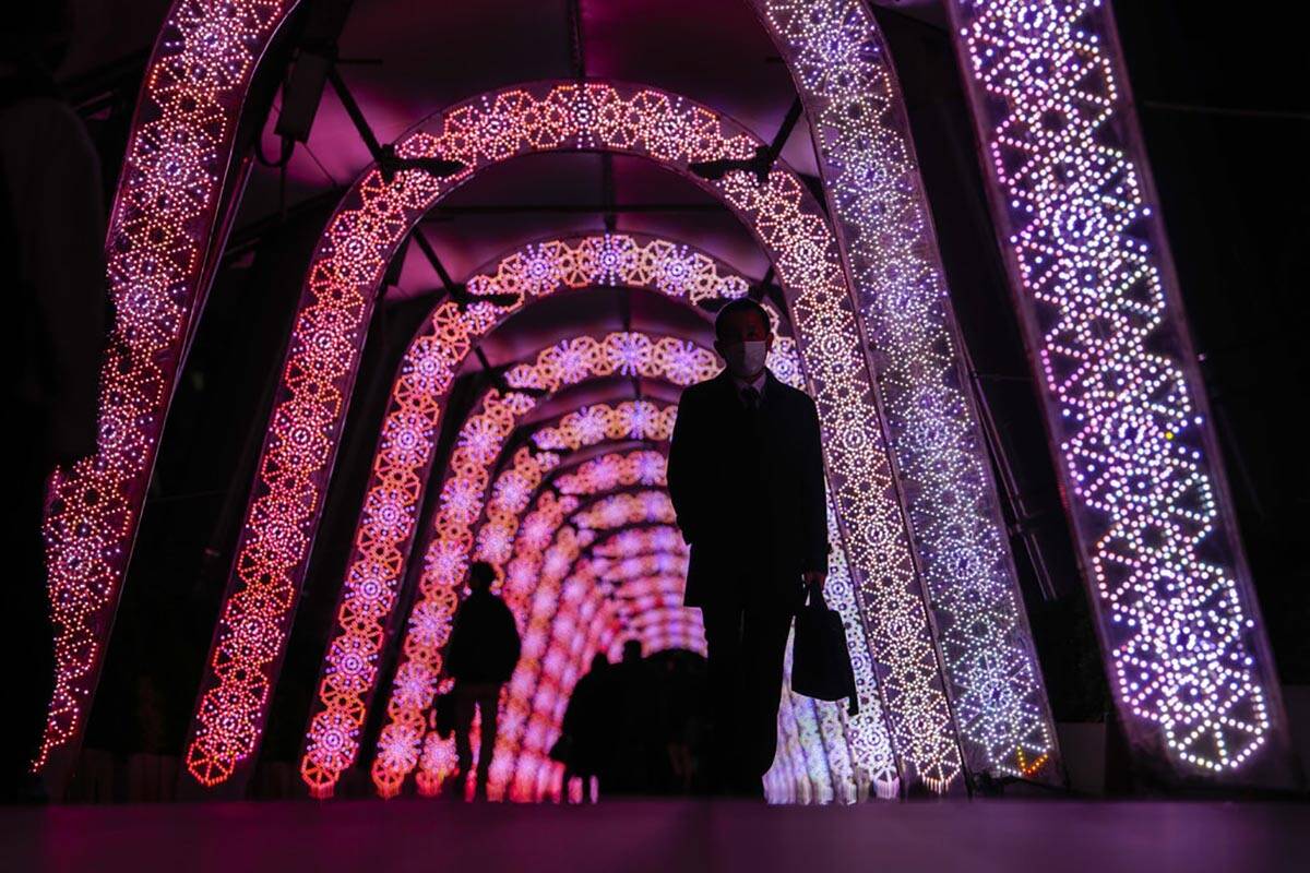 People walk through a tunnel of the holiday light displays Thursday, Dec. 9, 2021, in Tokyo. (A ...