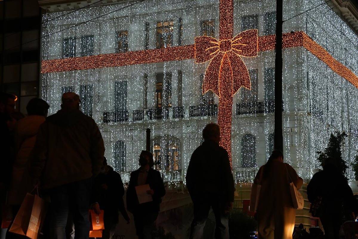 People walk in front of a Christmas decorated electronic store at Syntagma square in Athens, Gr ...