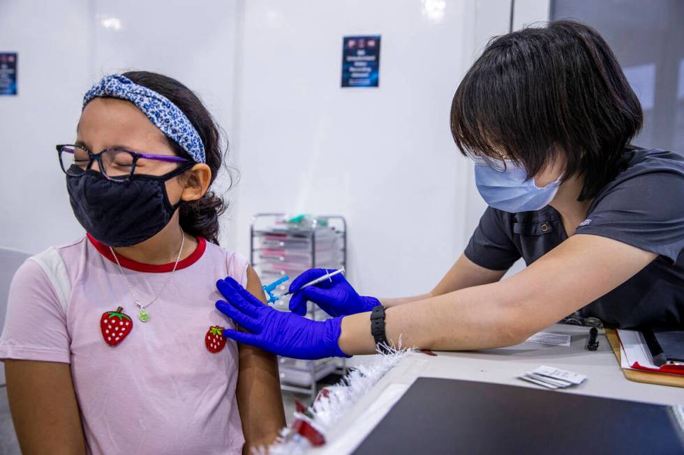 Noemi Flores Perez, 9, closes her eyes as Grisly Guerrero gives her a shot in the COVID-19 vacc ...