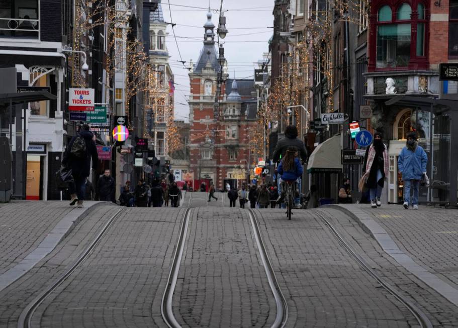 People walk down a normally bustling shopping street in the center of Amsterdam, Monday, Dec. 2 ...