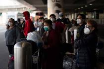 Travelers wait for a shuttle but to arrive at the Los Angeles International Airport in Los Ange ...