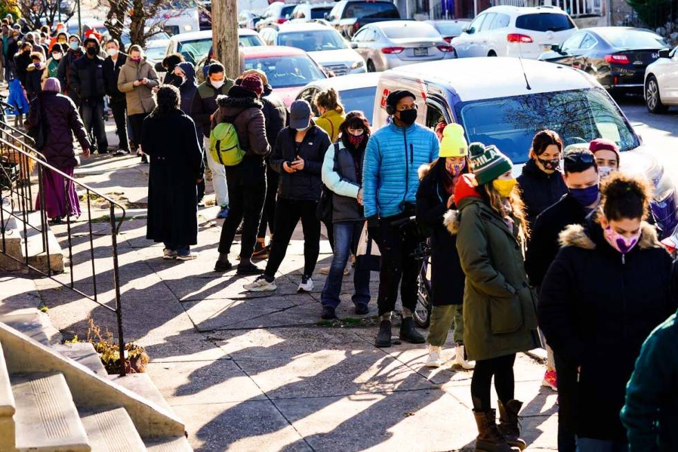 City residents wait in a line extending around the block to receive free at-home rapid COVID-19 ...