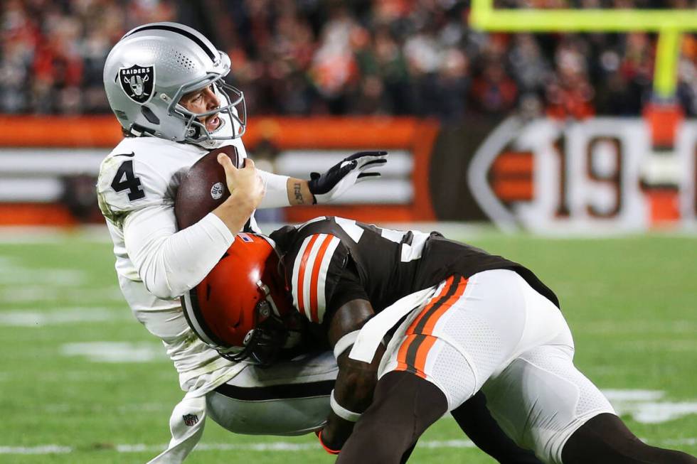 Raiders quarterback Derek Carr (4) is tackled by Cleveland Browns safety Jovante Moffatt (35) w ...