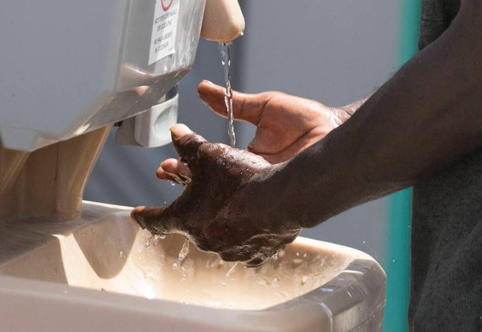 A man washes his hands at The Courtyard Homeless Resource Center in May 2020 in Las Vegas. (Biz ...