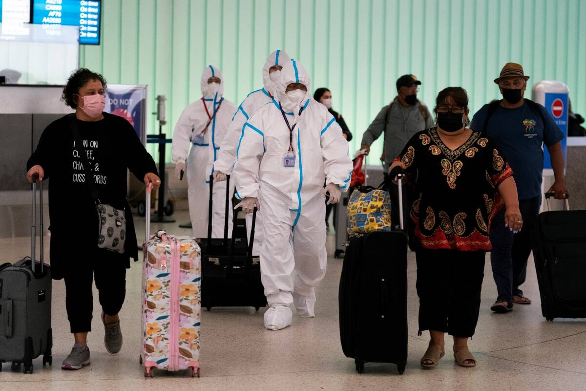 Air China flight crew members in hazmat suits walk through the arrivals area at Los Angeles Int ...