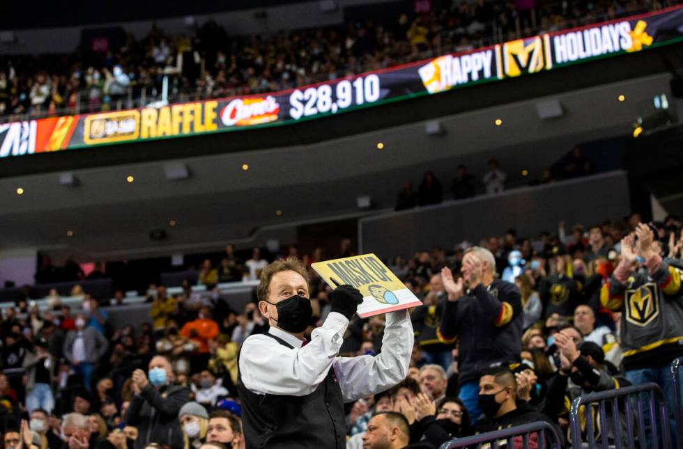 A Golden Knights usher holds a mask up sign during an NHL hockey game against the Tampa Bay Lig ...
