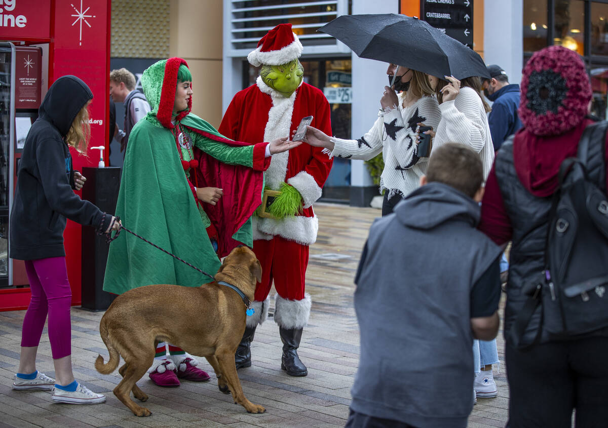 The Grinch and his helper entertain shoppers in the rain during some last minute shopping at Do ...
