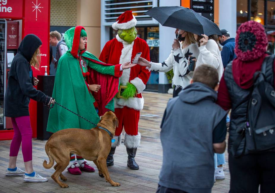 The Grinch and his helper entertain shoppers in the rain during some last minute shopping at Do ...