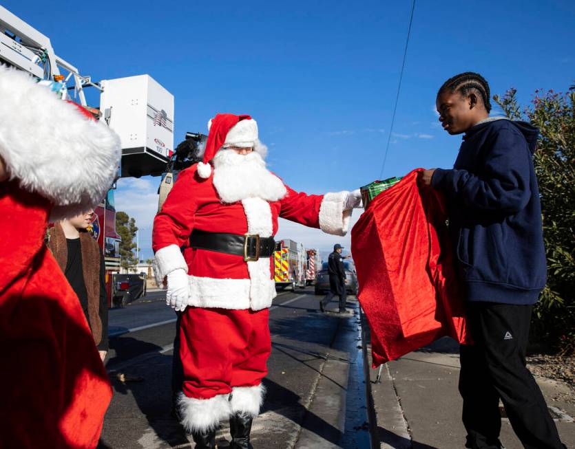 Damien Holland (15) receives gifts from Santa at his residence on Friday, Dec. 24, 2021, in Nor ...