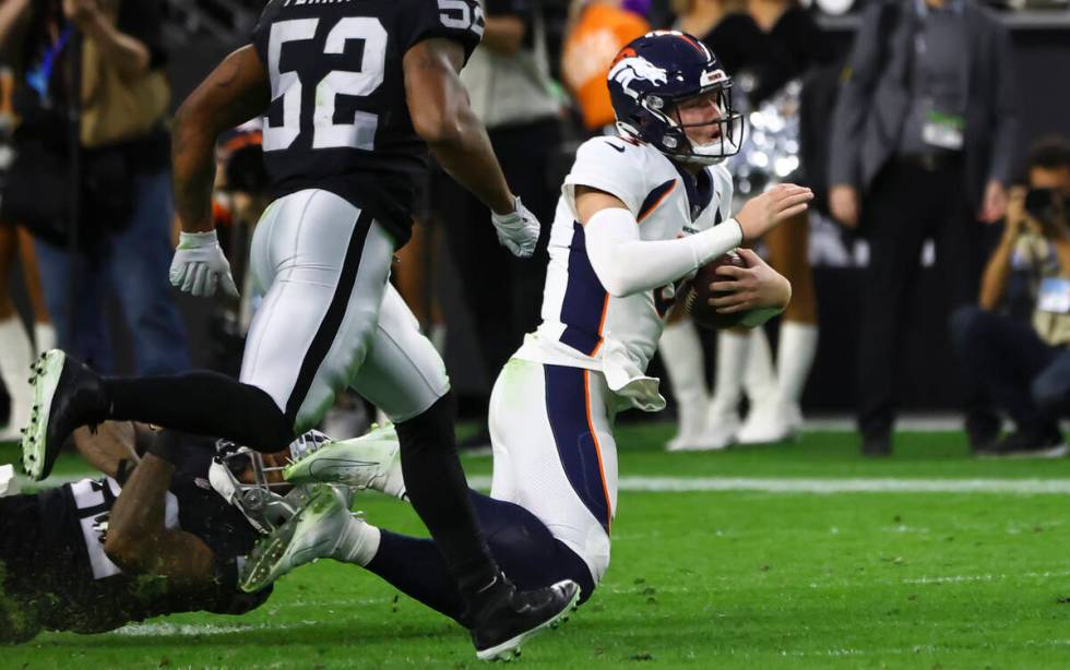 Denver Broncos quarterback Drew Lock, right, gets tripped up by Raiders defensive back Keisean ...