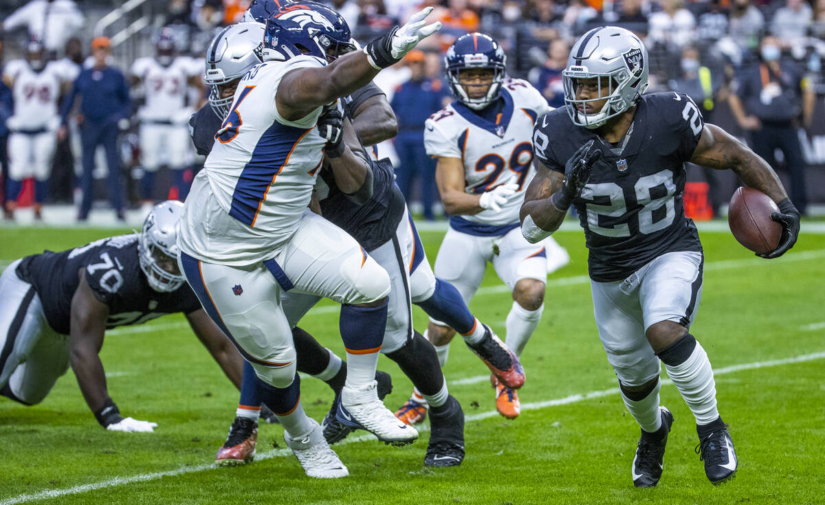 Raiders running back Josh Jacobs (28) looks to turn the corner on Denver Broncos defensive end ...