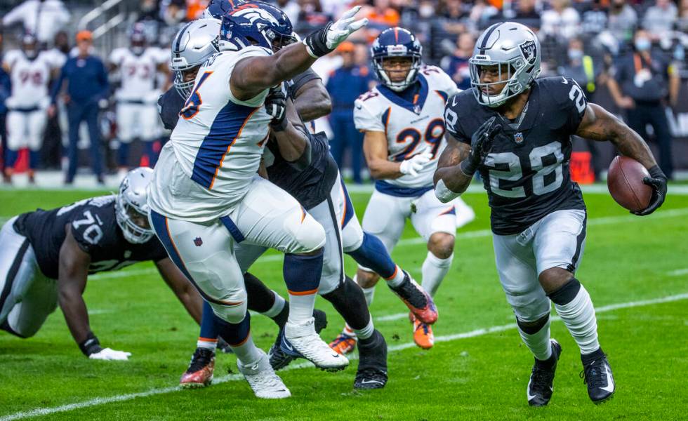 Raiders running back Josh Jacobs (28) looks to turn the corner on Denver Broncos defensive end ...