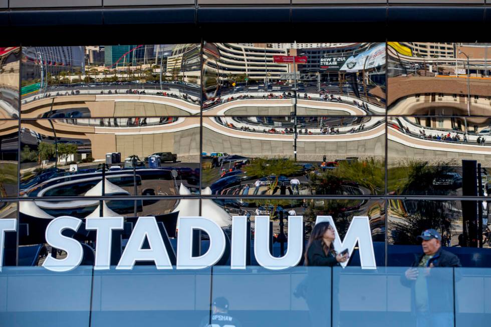 Raiders and Denver Broncos fans are reflected in the north side windows before the first half o ...