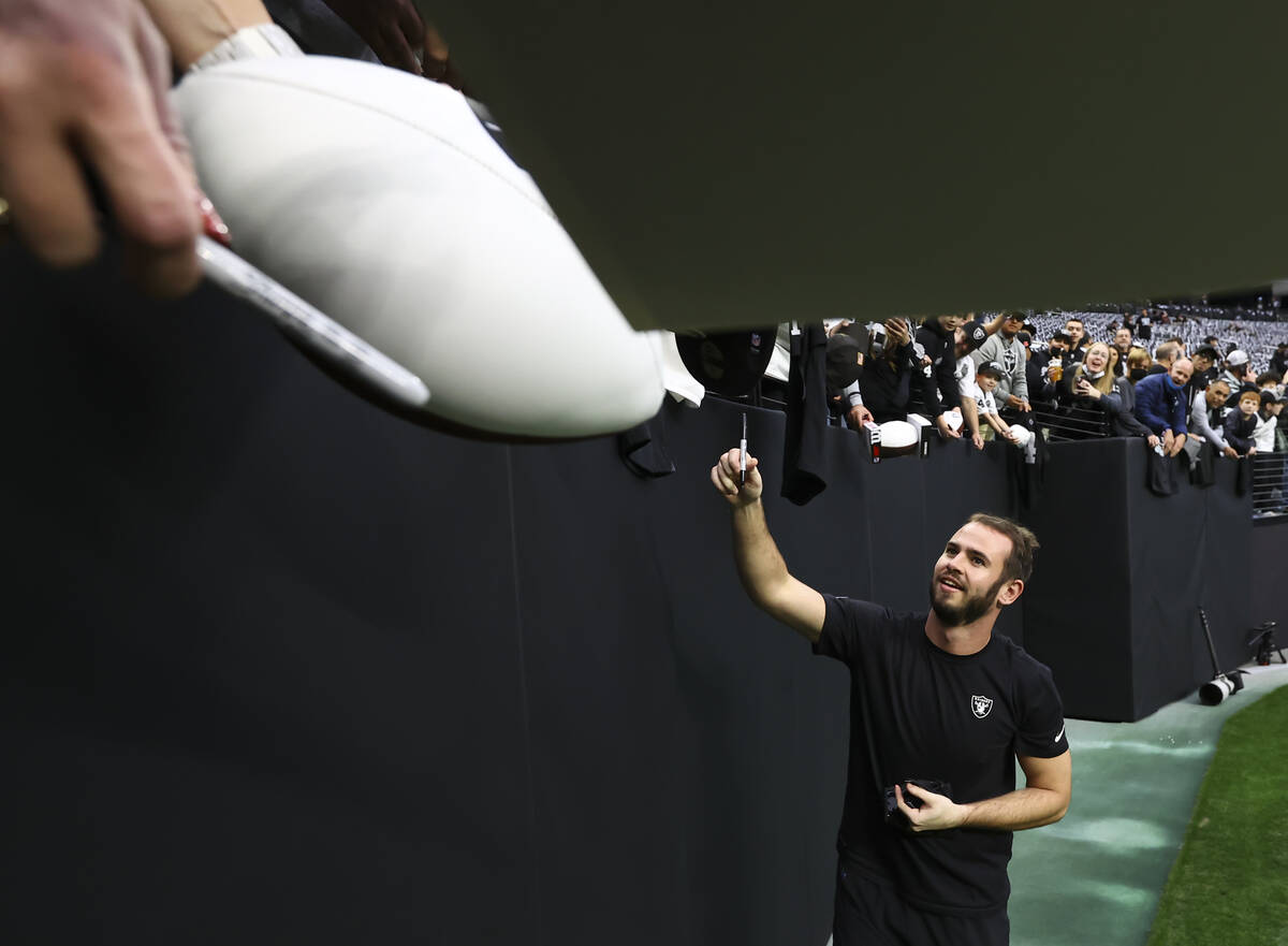 Raiders wide receiver Hunter Renfrow signs items for fans before an NFL football game against t ...