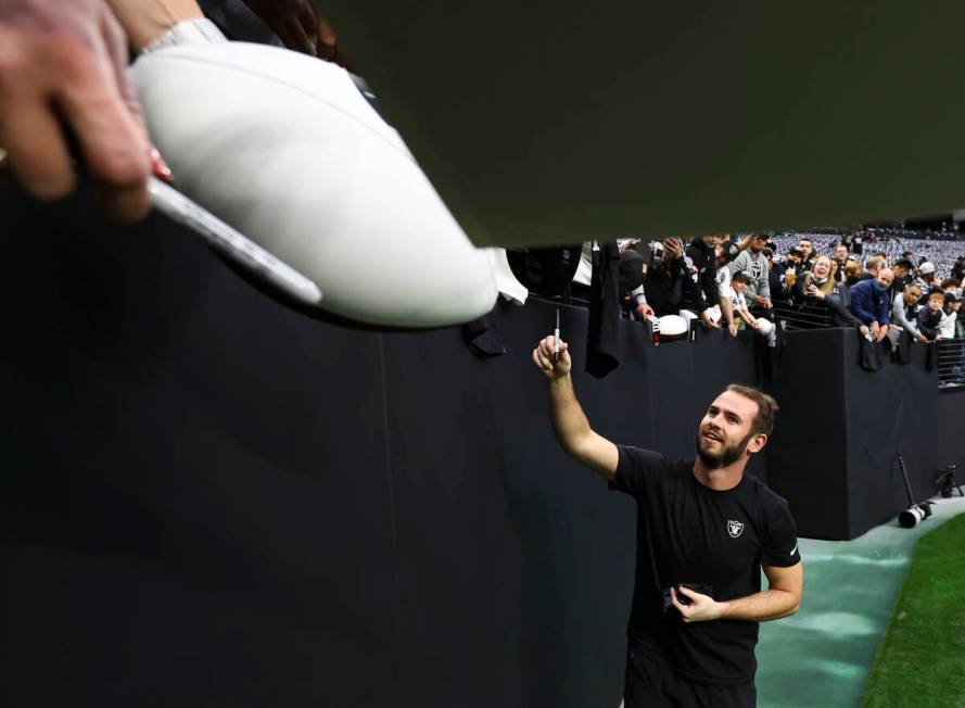 Raiders wide receiver Hunter Renfrow signs items for fans before an NFL football game against t ...