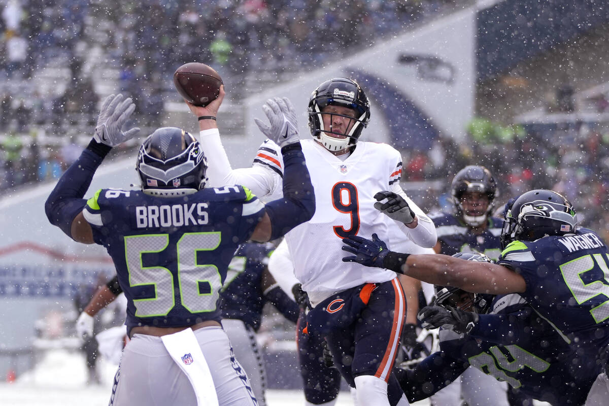 Chicago Bears quarterback Nick Foles (9) passes between Seattle Seahawks' Jordyn Brooks (56) an ...