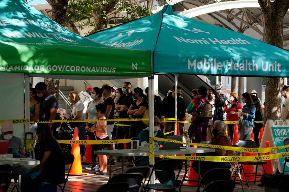 Dozens of people wait in line to be tested for COVID-19, alongside other tents with no line whe ...