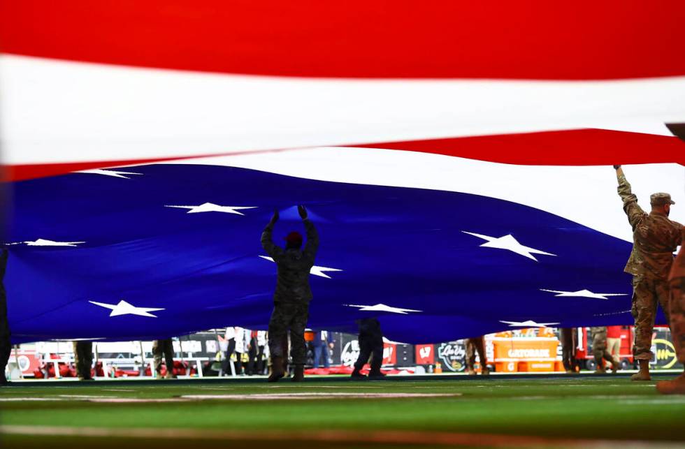 Members of the military and law enforcement display the U.S. flag across the field before the L ...