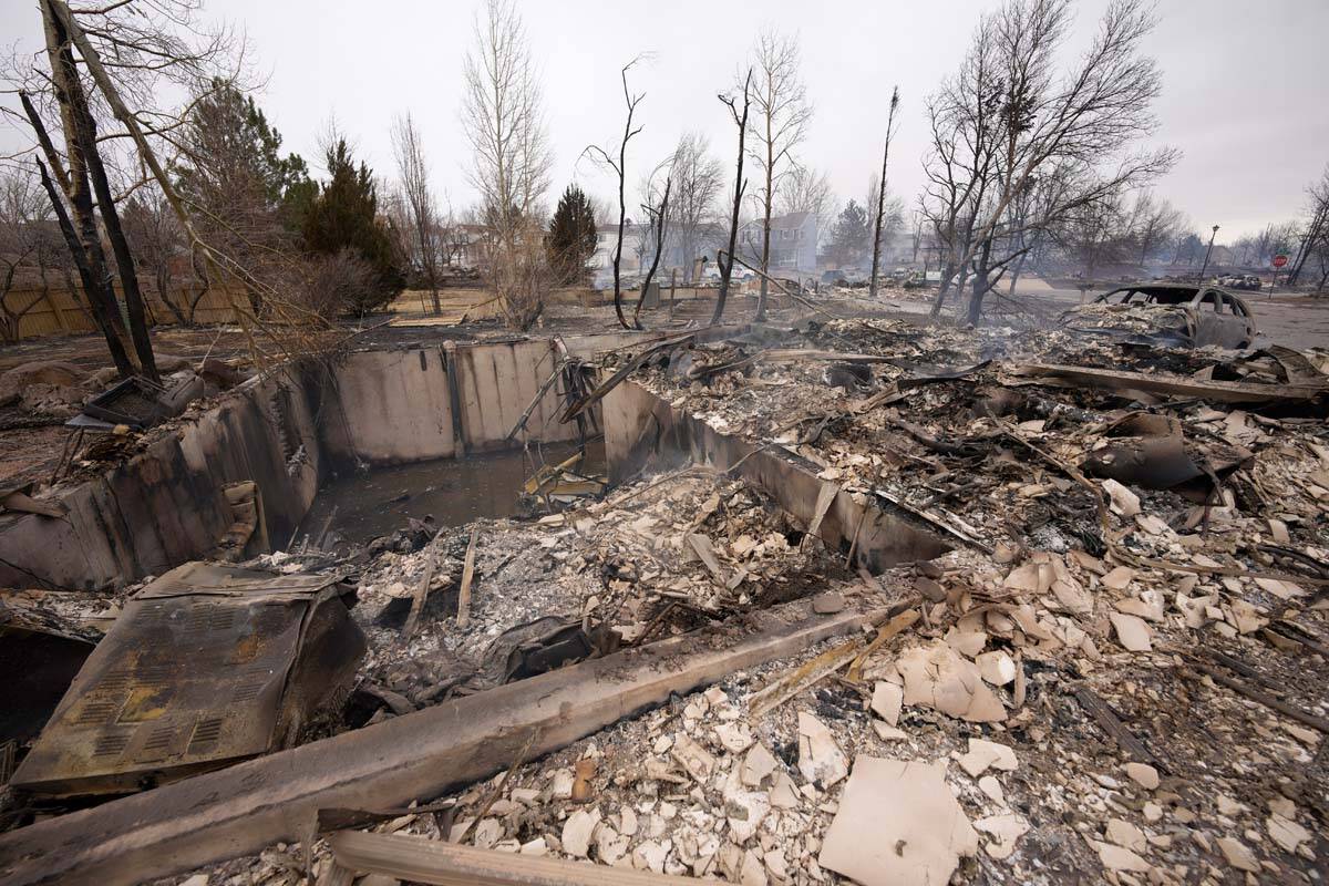 Debris surrounds the remains of homes burned by wildfires after they ripped through a developme ...