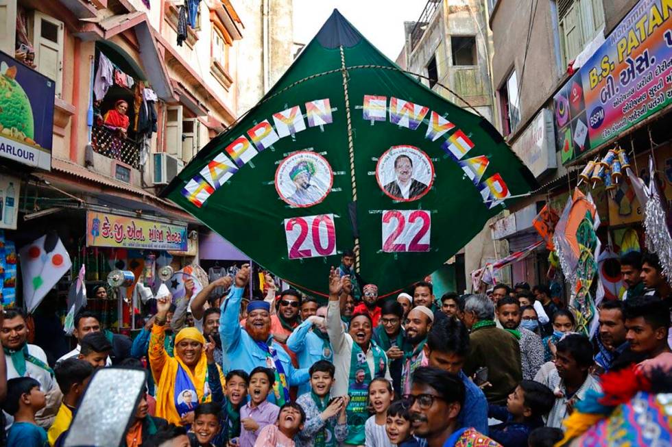 Workers of a political party and others cheer in front of a huge kite to welcome 2022 on New Ye ...