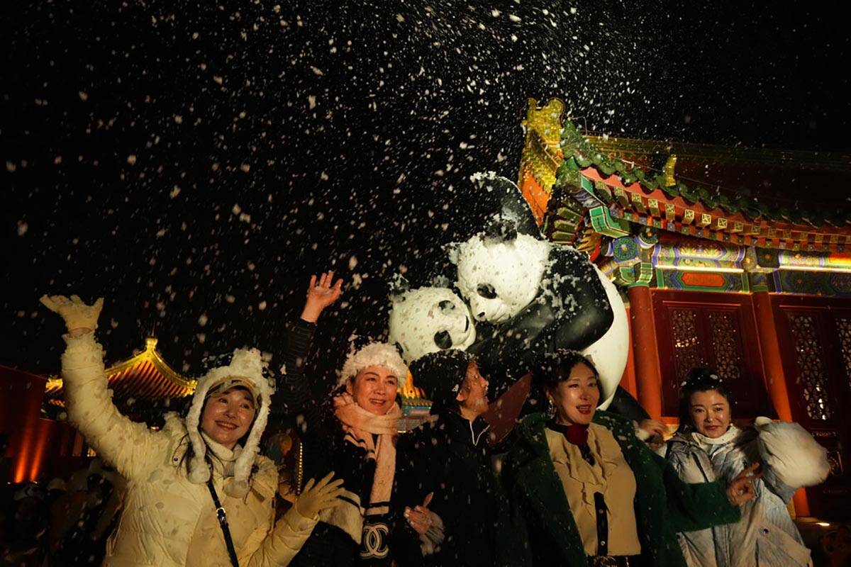 Attendees at an event that coincided with the New Year Eve cheer as fake snow from a foam machi ...