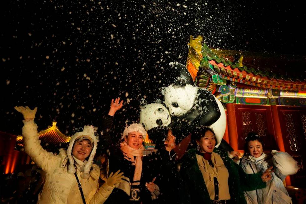 Attendees at an event that coincided with the New Year Eve cheer as fake snow from a foam machi ...