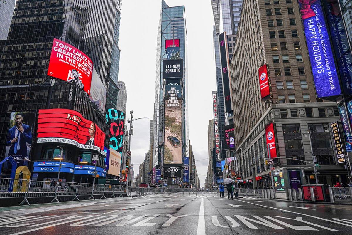 FILE - Pedestrians walk in a nearly empty Times Square ahead of the New Year's Eve celebration ...