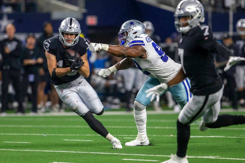 Raiders wide receiver Hunter Renfrow (13) looks for room to run as Dallas Cowboys defensive end ...