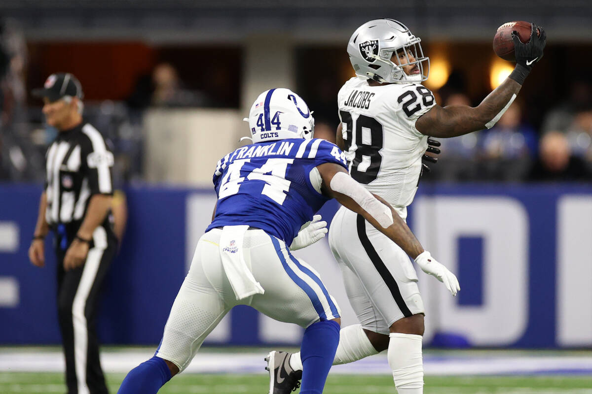 Raiders running back Josh Jacobs (28) makes a catch under pressure from Indianapolis Colts outs ...