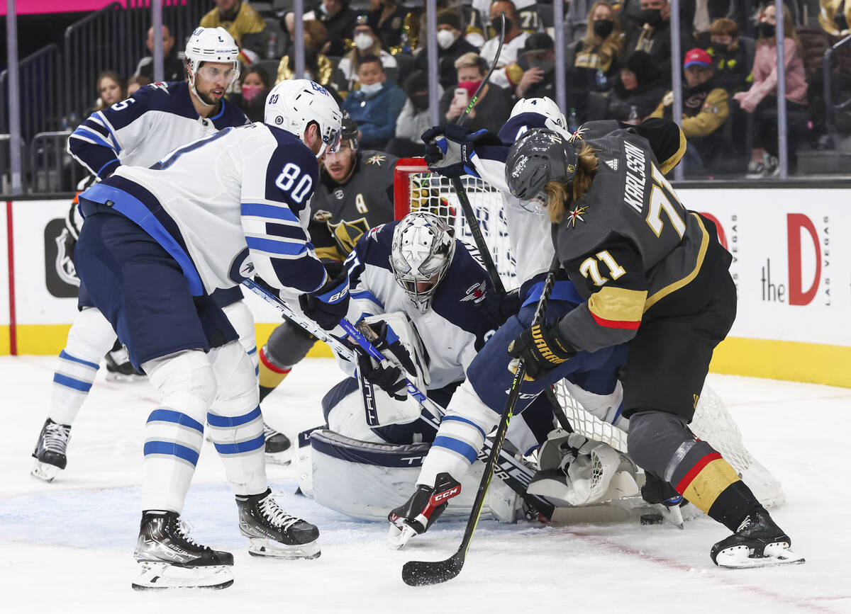 Winnipeg Jets goaltender Connor Hellebuyck, center, and left wing Pierre-Luc Dubois (80) defend ...