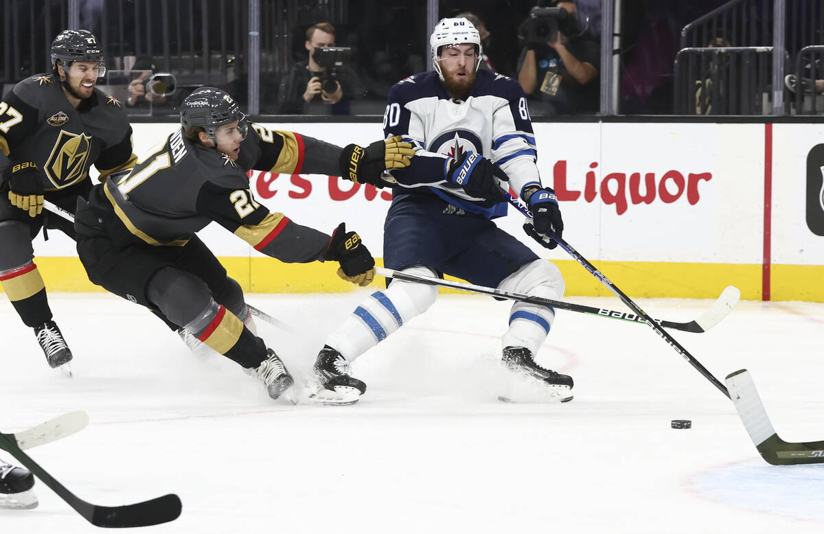 Golden Knights center Brett Howden (21) tries to get the puck from Winnipeg Jets left wing Pier ...