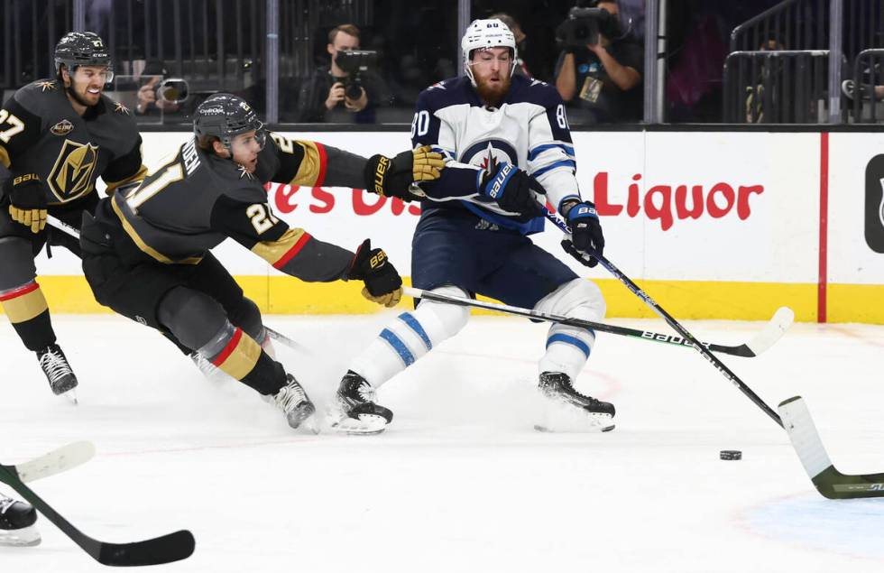 Golden Knights center Brett Howden (21) tries to get the puck from Winnipeg Jets left wing Pier ...