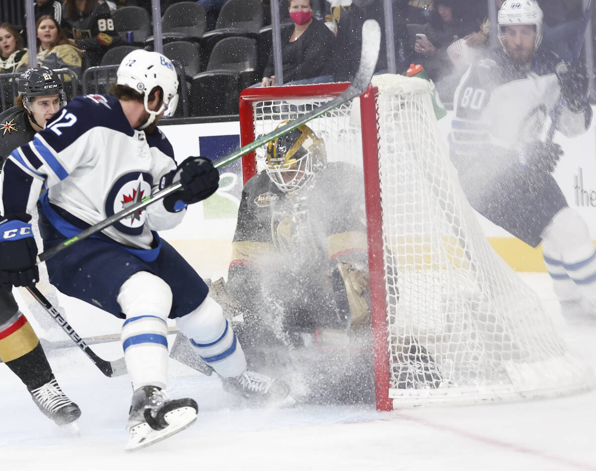 Golden Knights goaltender Laurent Brossoit (39) makes a save in front of Winnipeg Jets center J ...