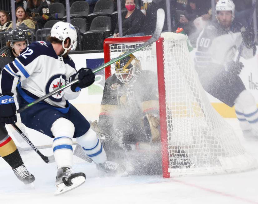 Golden Knights goaltender Laurent Brossoit (39) makes a save in front of Winnipeg Jets center J ...